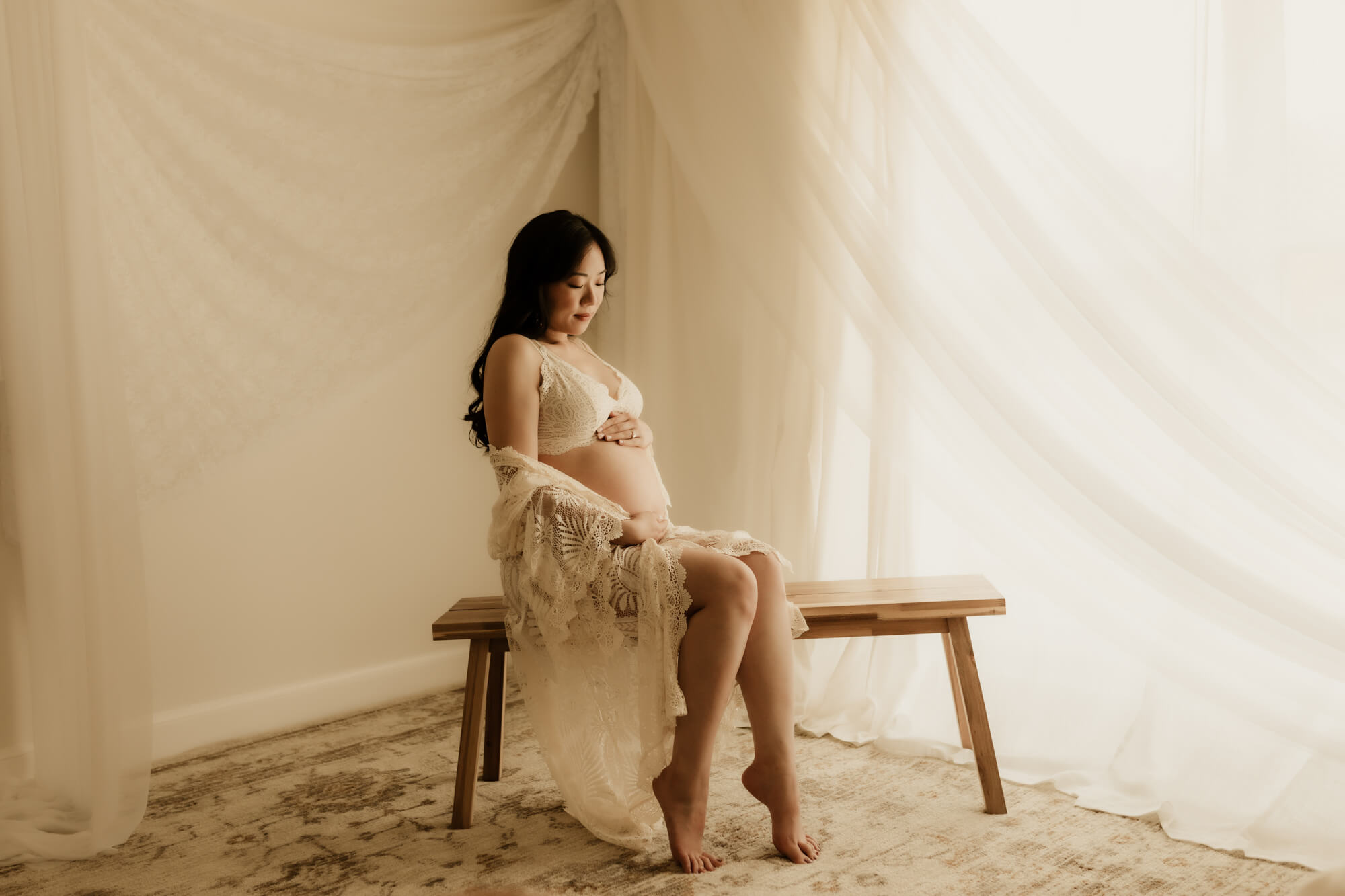 Expecting mother looking at her baby bump while sitting on a bench, prenatal massage okc.