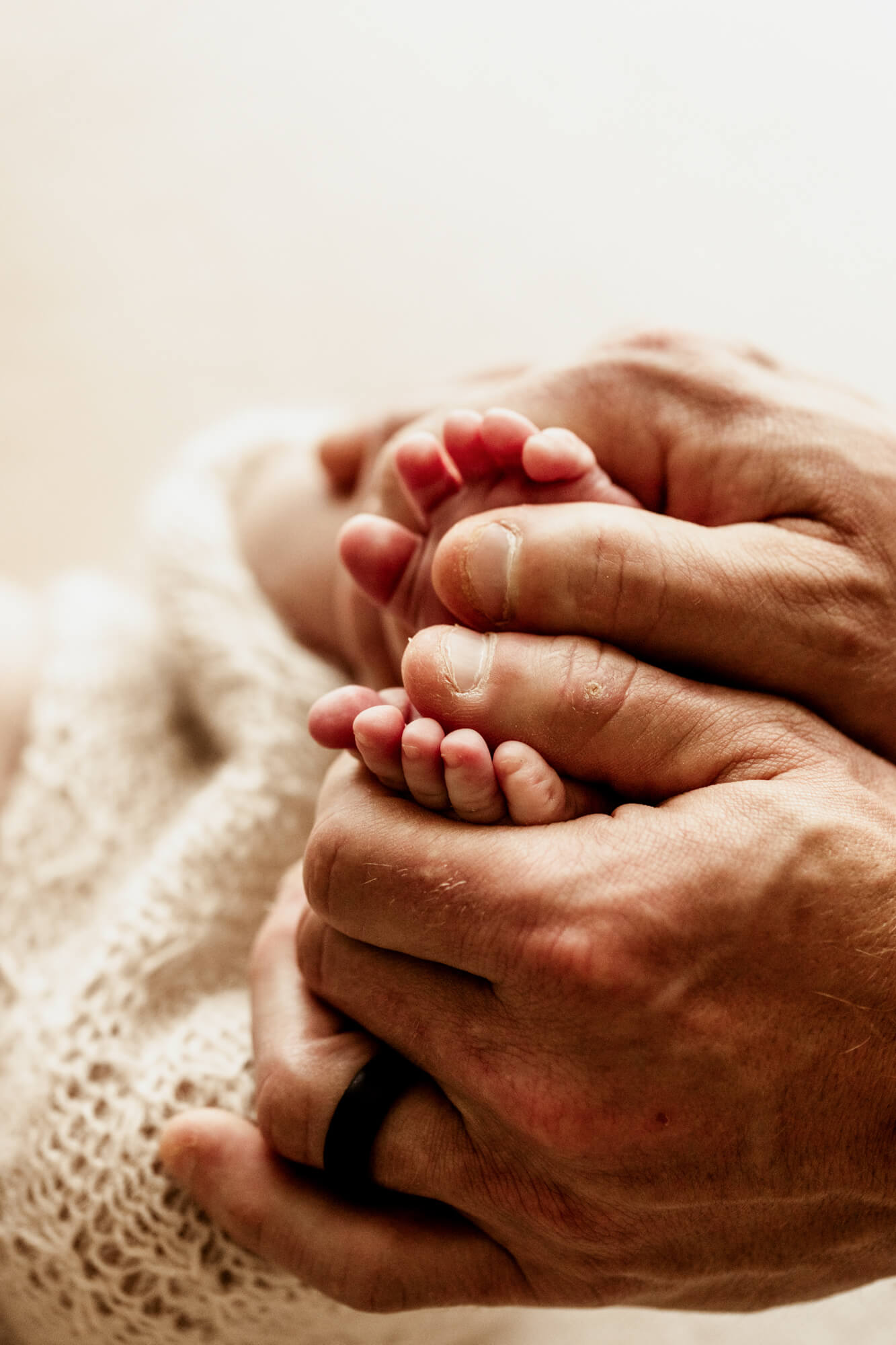 Newborn baby feet contrasted with father's hands holding them.