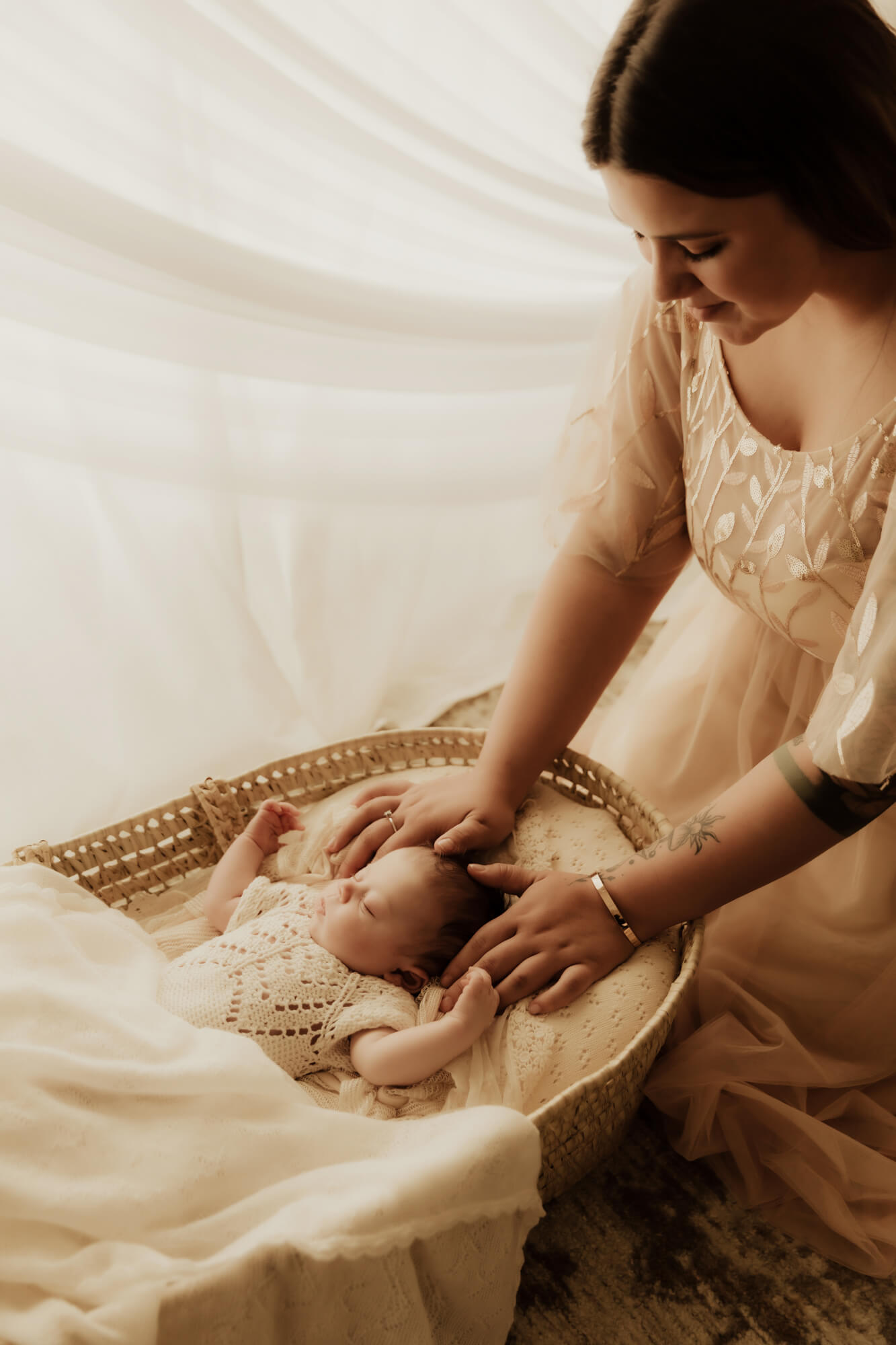 A new mother kneels over her sleeping newborn baby in a wicker basket interior designer okc