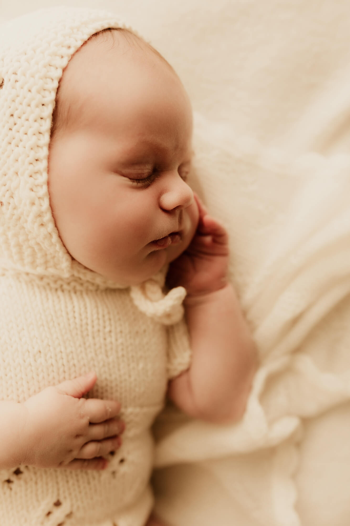 Sleeping newborn baby girl with her hand near her cheek.