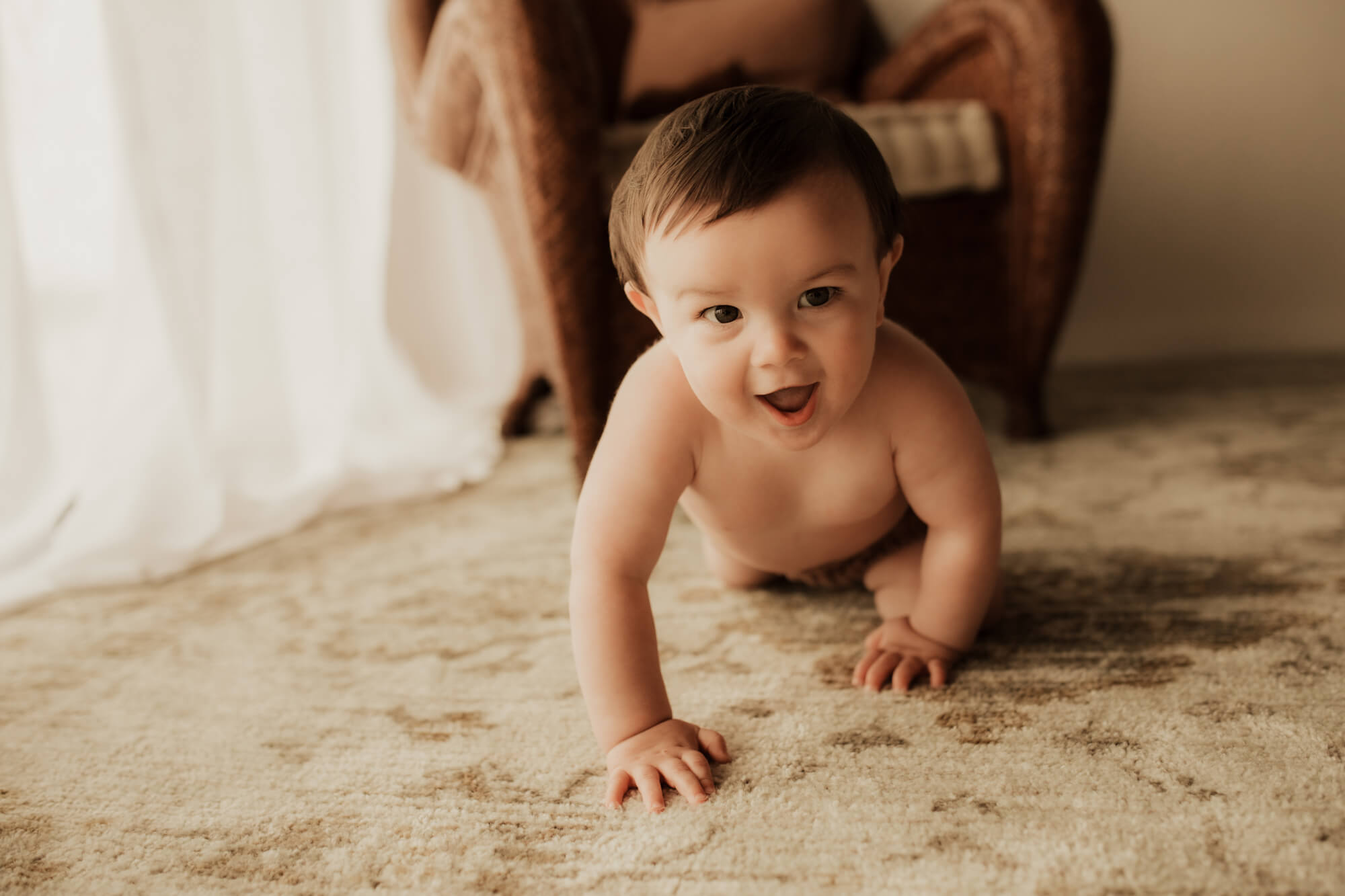 Excited boy crawls on a rug, okc family activities.