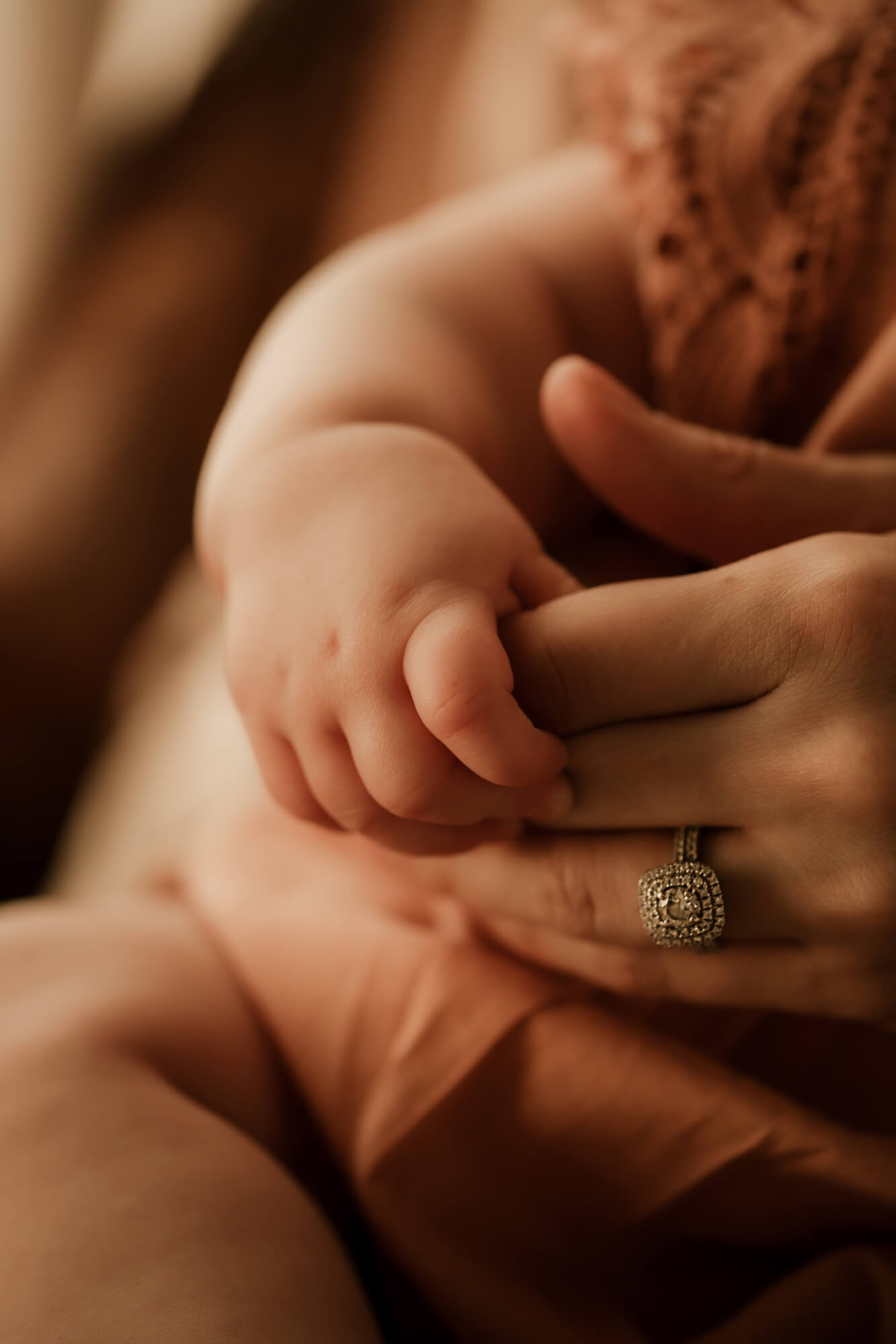 Baby girl holds her mother's hand.