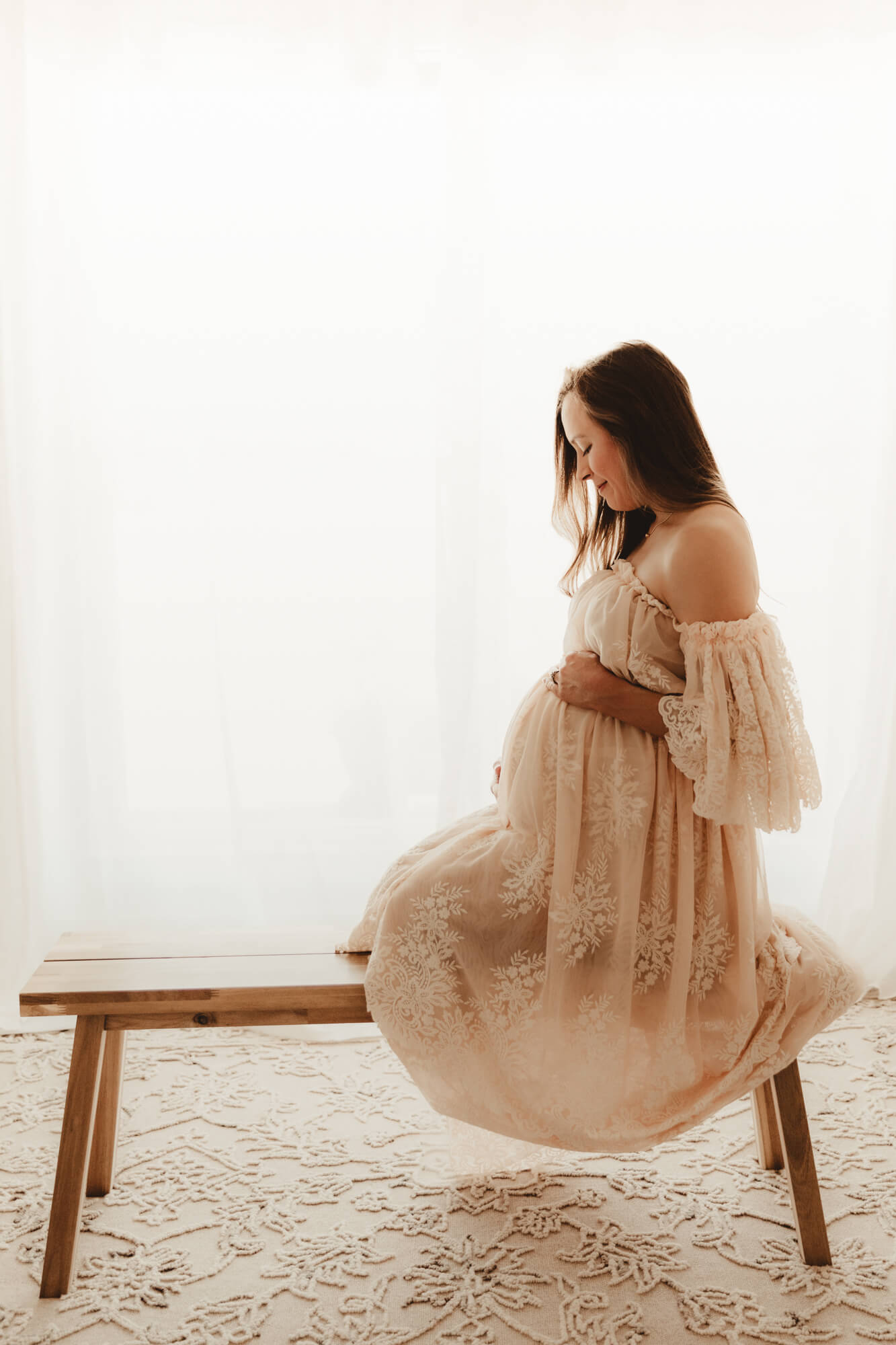 Pregnancy photo of woman on a bench looking at her baby bump, Dr Goff OKC.