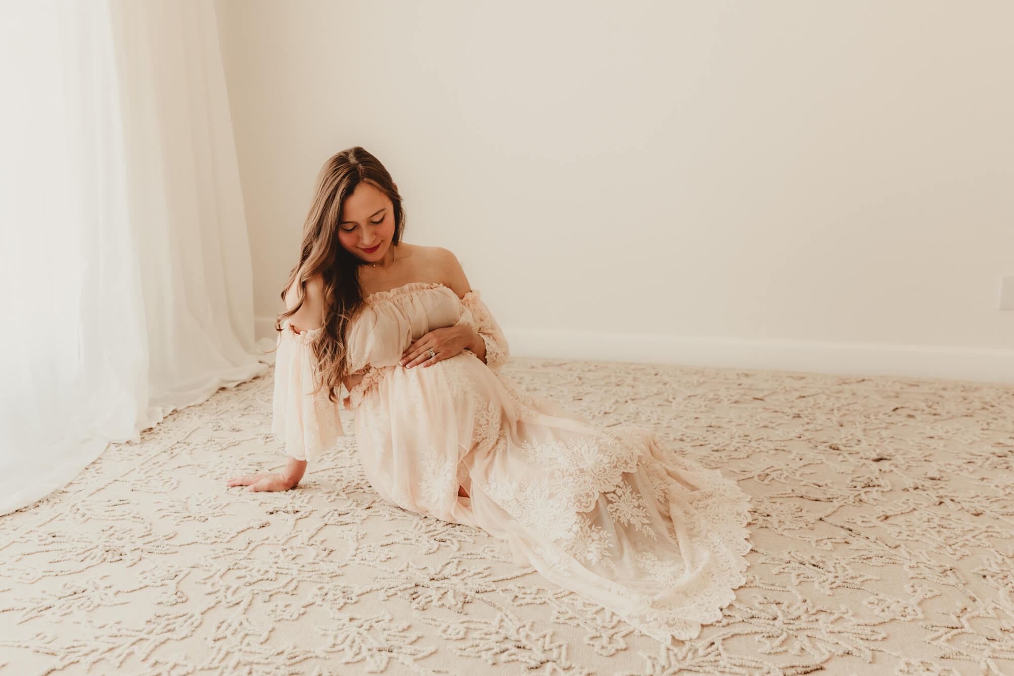 Pregnancy photo of woman looking at her belly while sitting down, Dr Goff OKC.