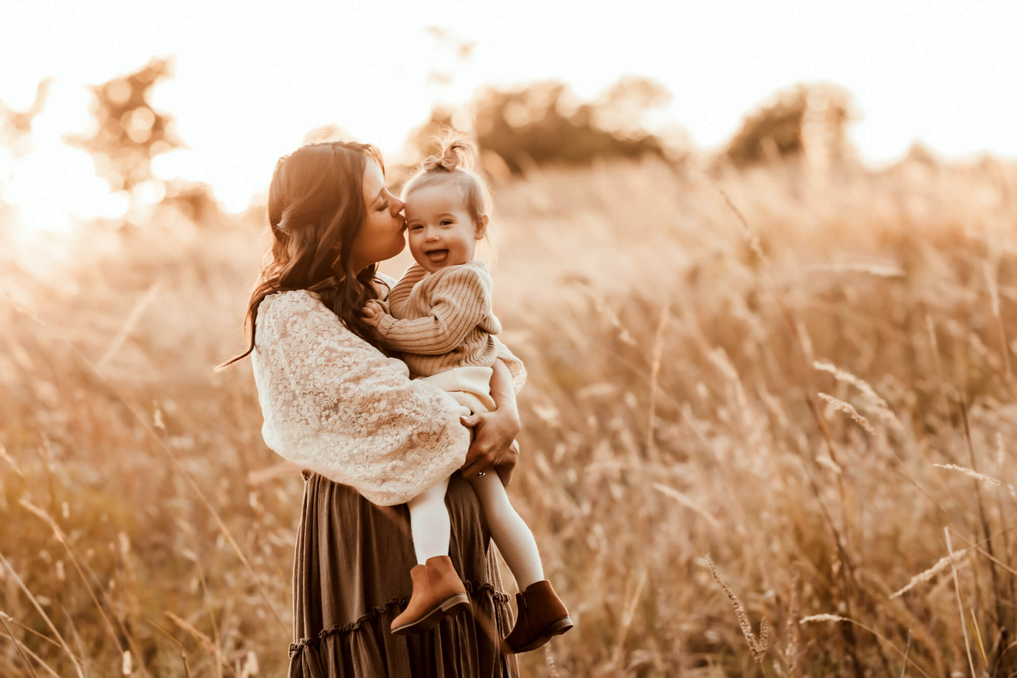 Mother wearing a boho skirt and dress kisses her daughter on the cheek, okc parks.