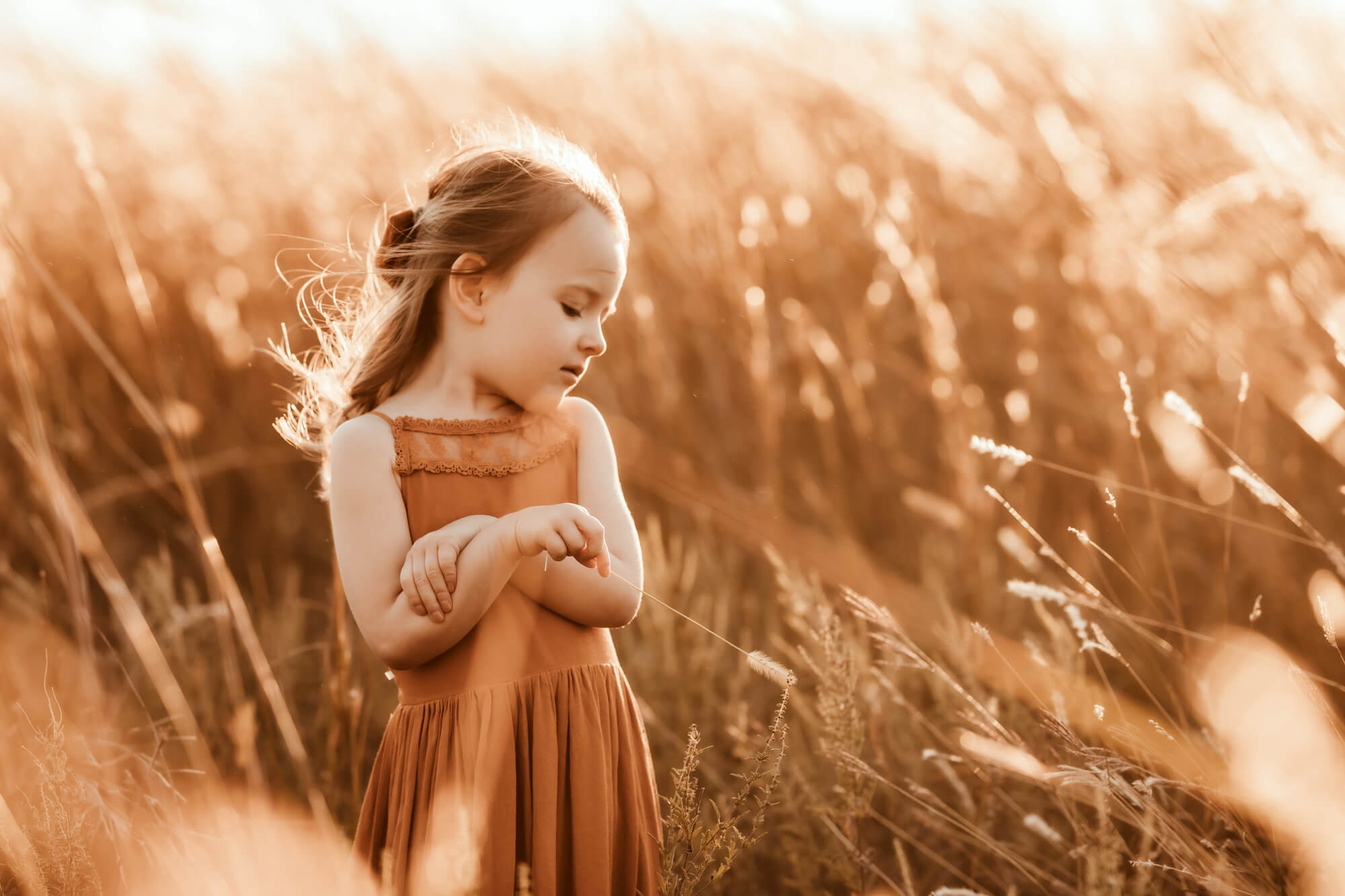 Girl wearing an orange dress plays in a field with the grass, okc parks.