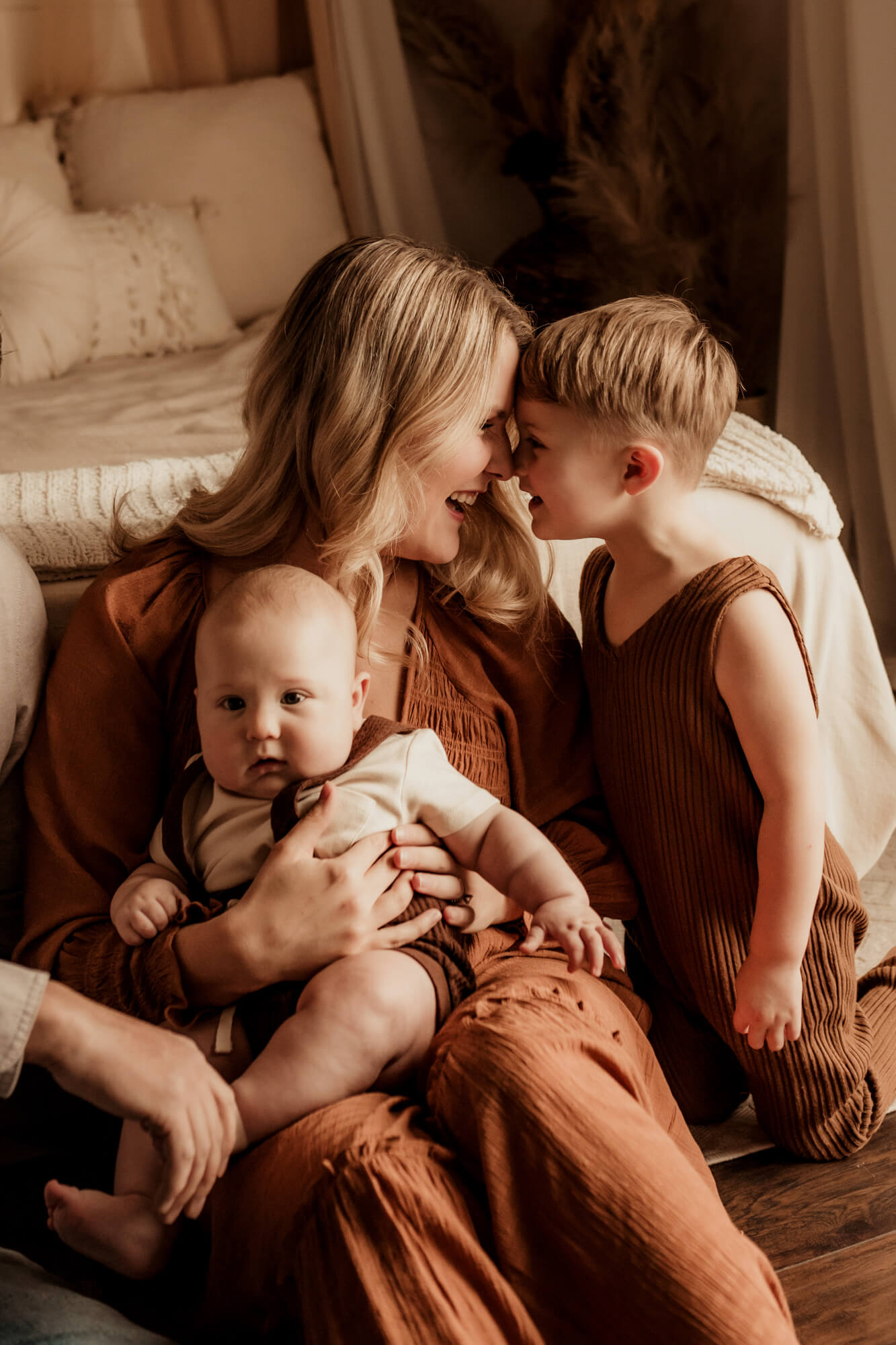 Mother and son touch noses while baby boy sits in her lap