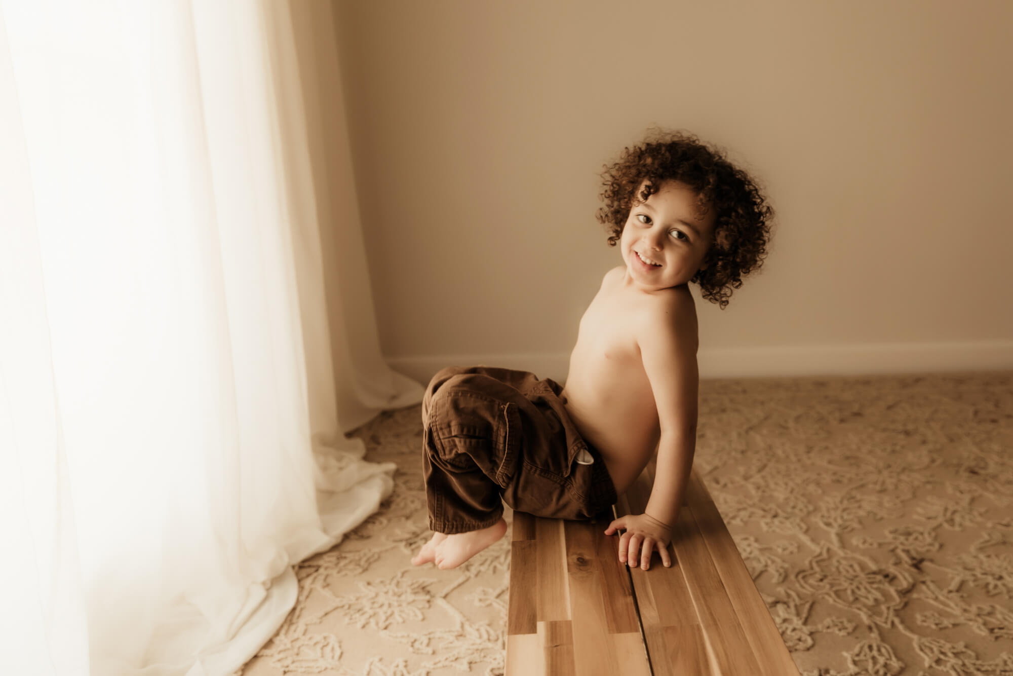 Boy with curly hair sitting on a bench