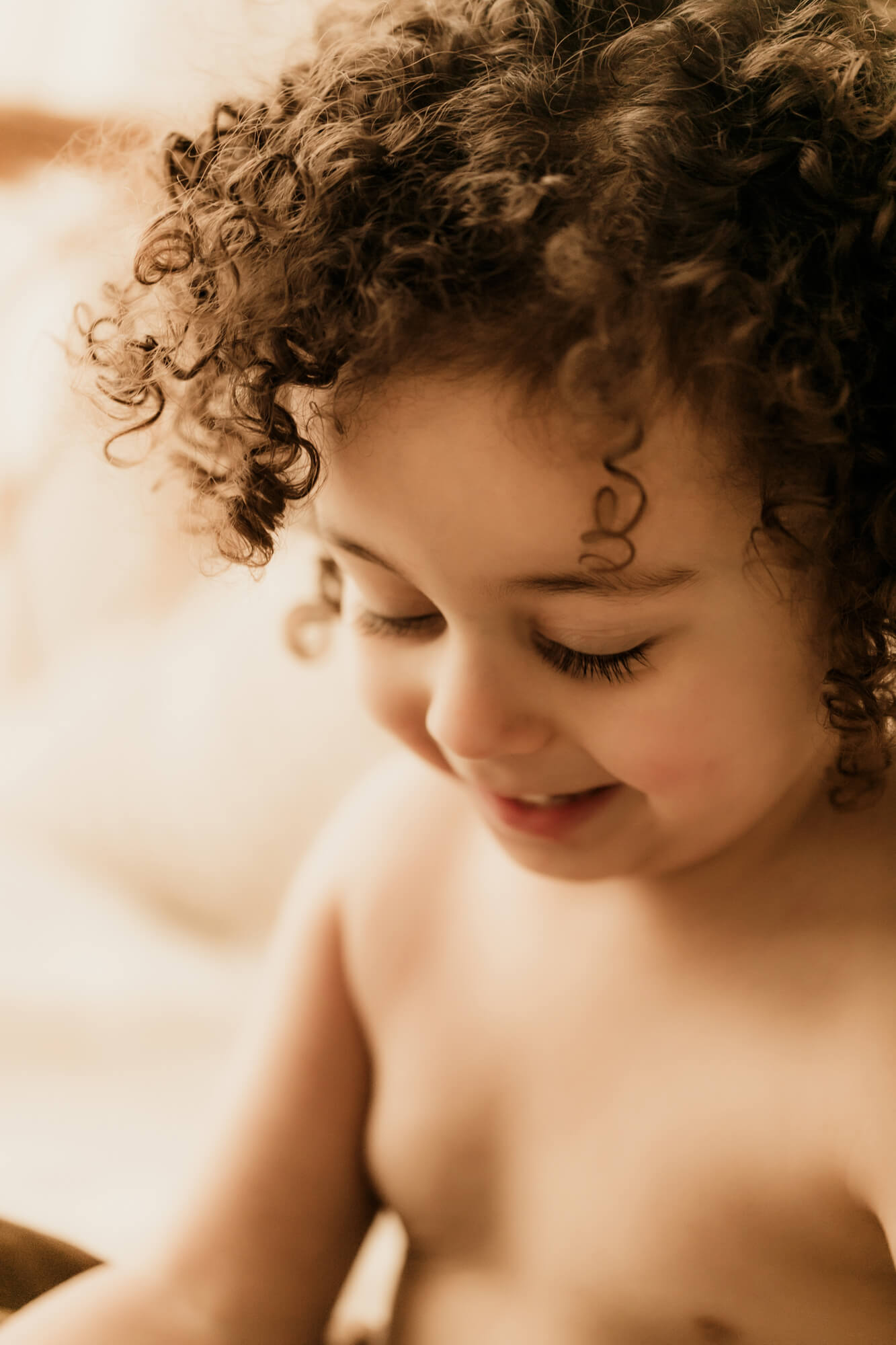 Little boy with curly hair smiles while looking down, Sharkey's Cuts for Kids