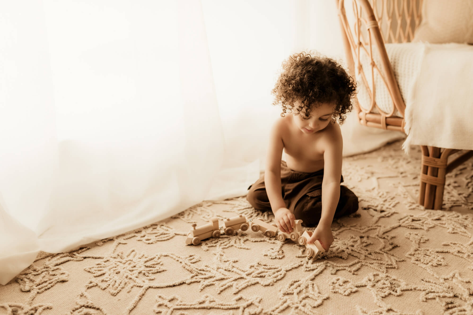 Little boy plays with a wooden train on the floor, Sharkey's Cuts for Kids