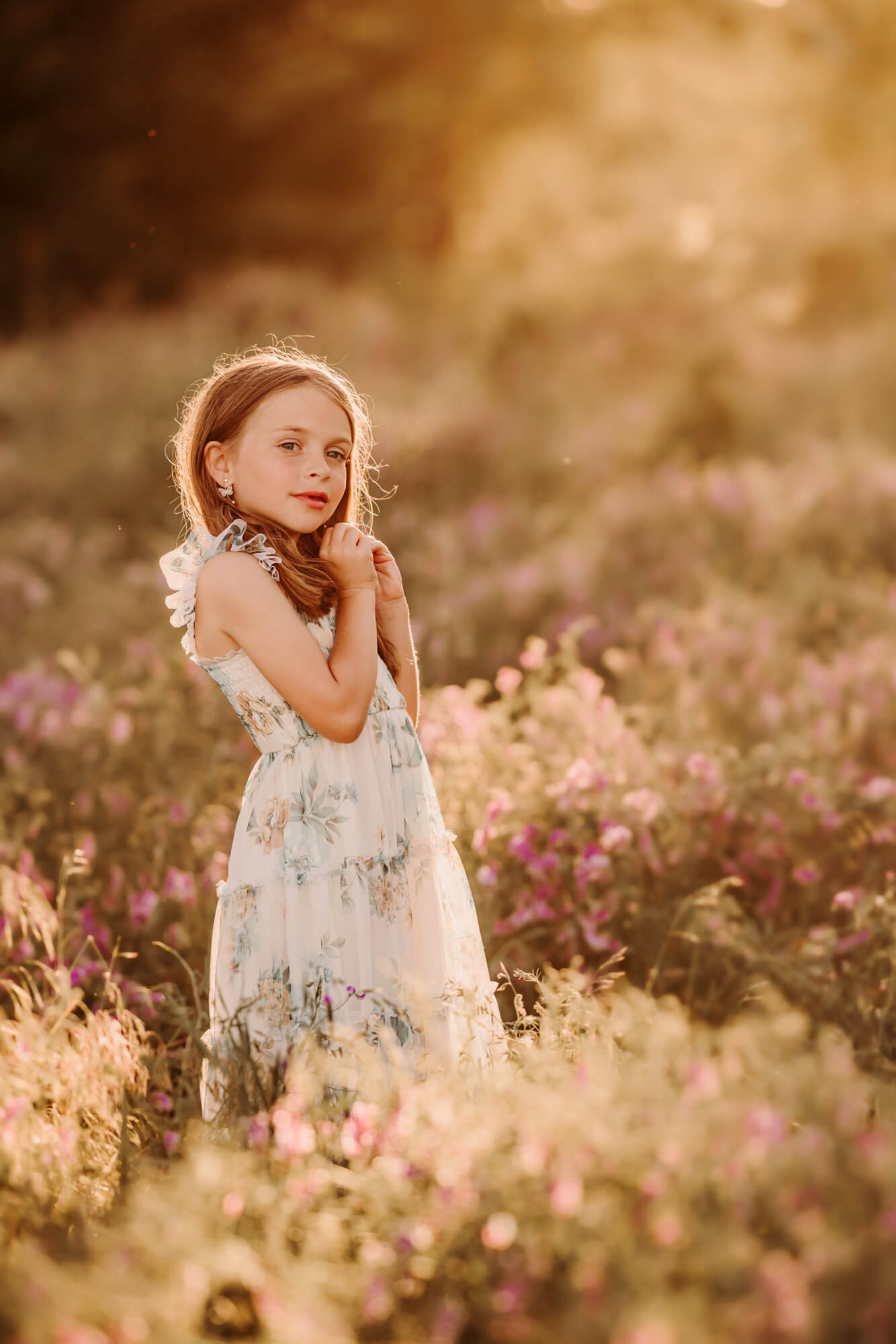 Girl in a white and blue floral dress has her hands near her face, OKC swim lessons.