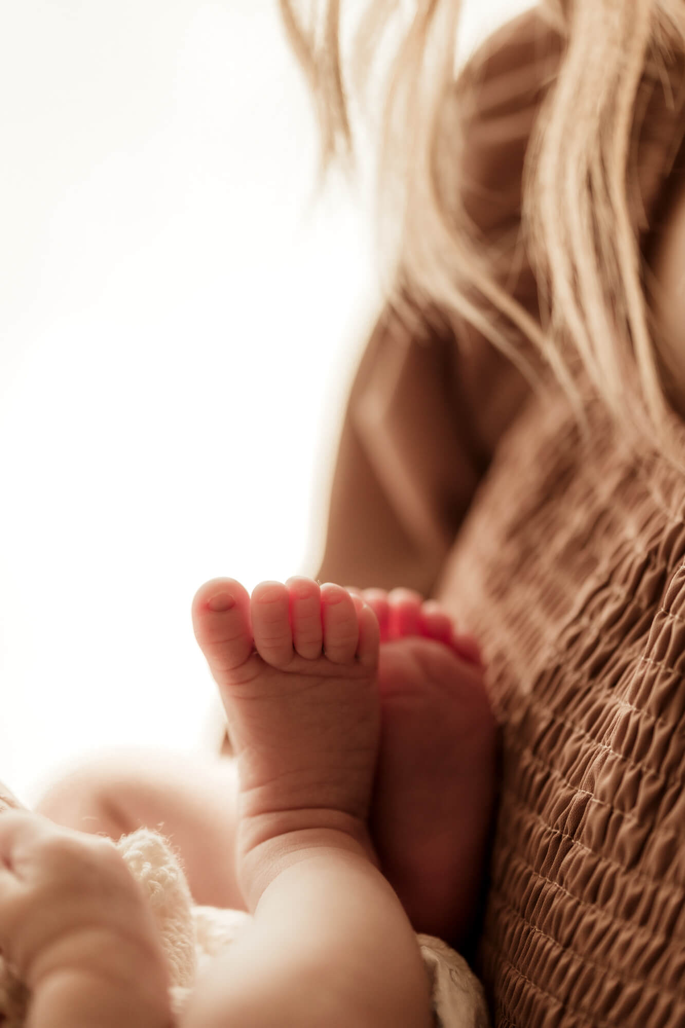 Details of a newborn baby's feet against mom's chest
