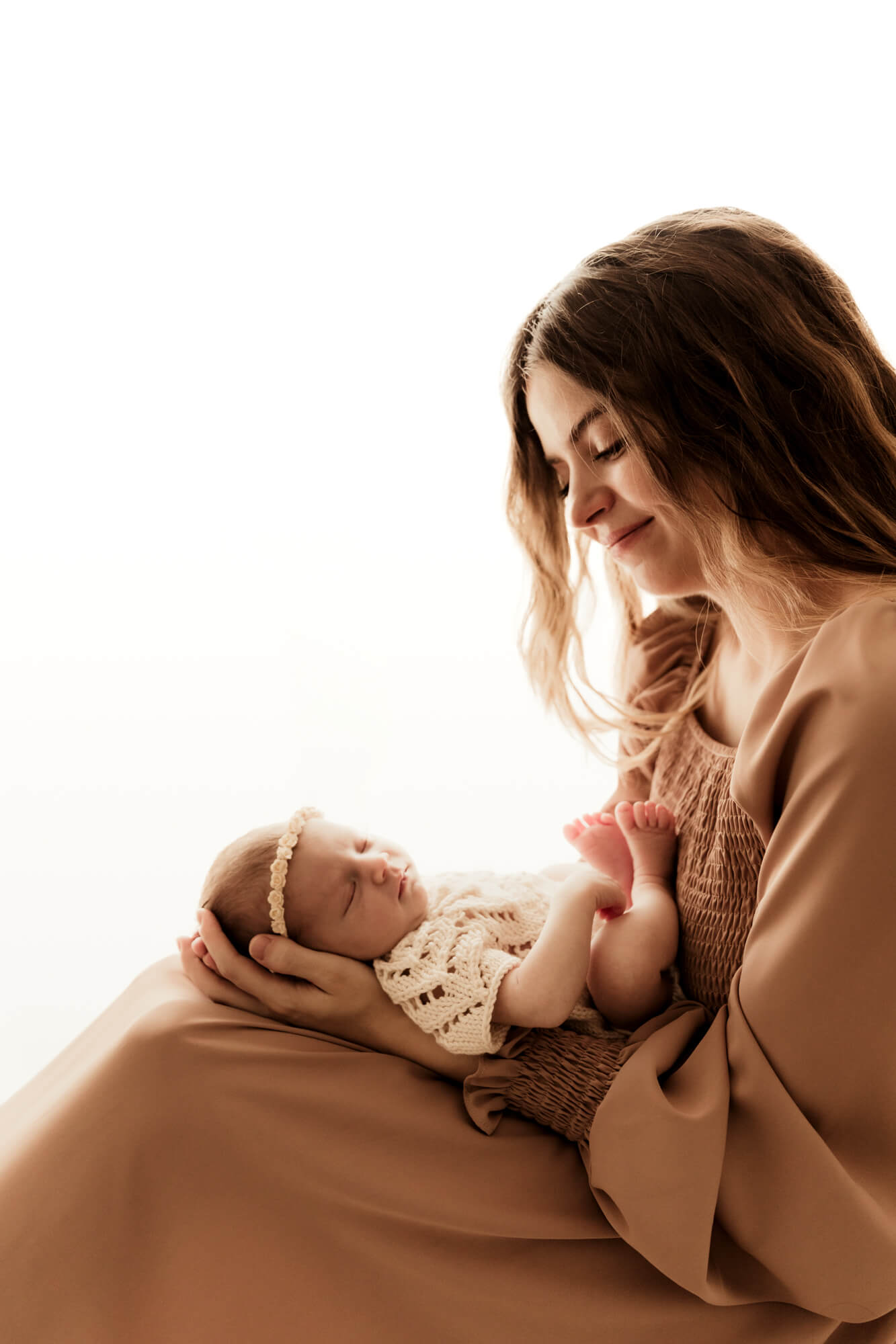 A happy mom to be smiles down at her sleeping baby girl in her lap after some OKC parenting classes