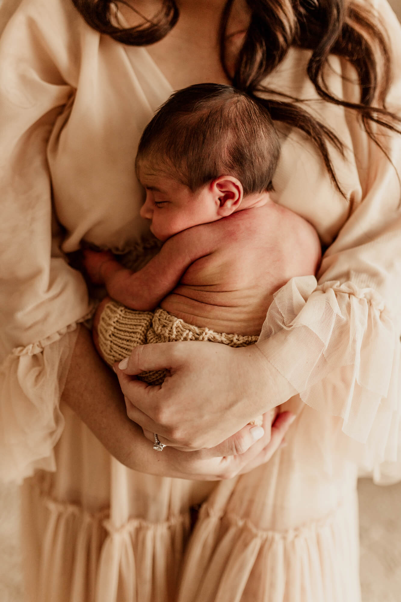 A newborn baby sleeps against mom's chest in her hands as she stands thanks to Oklahoma fertility clinics