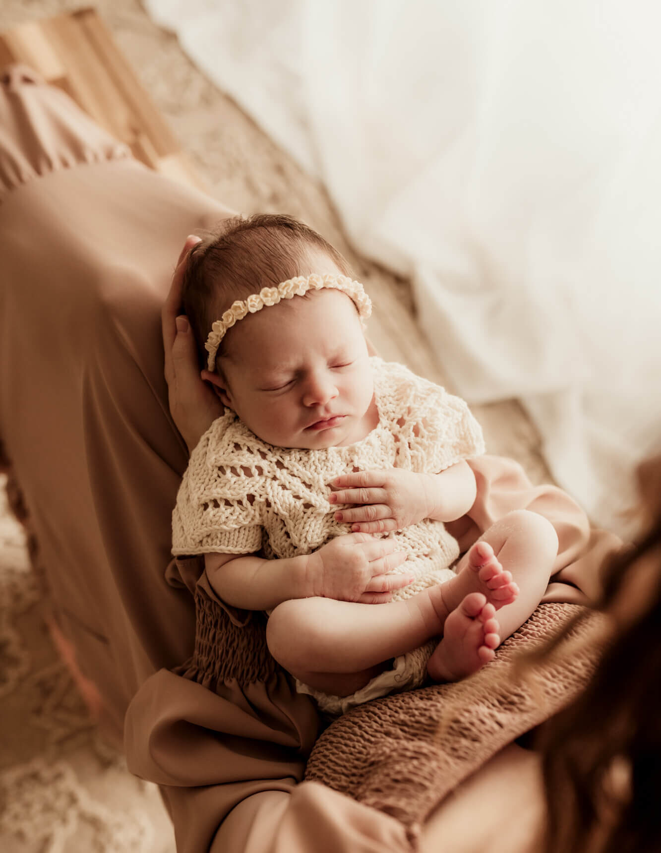 A newborn baby in a knit onesie sleeps in mom's lap after visiting Tin Lizzies OKC