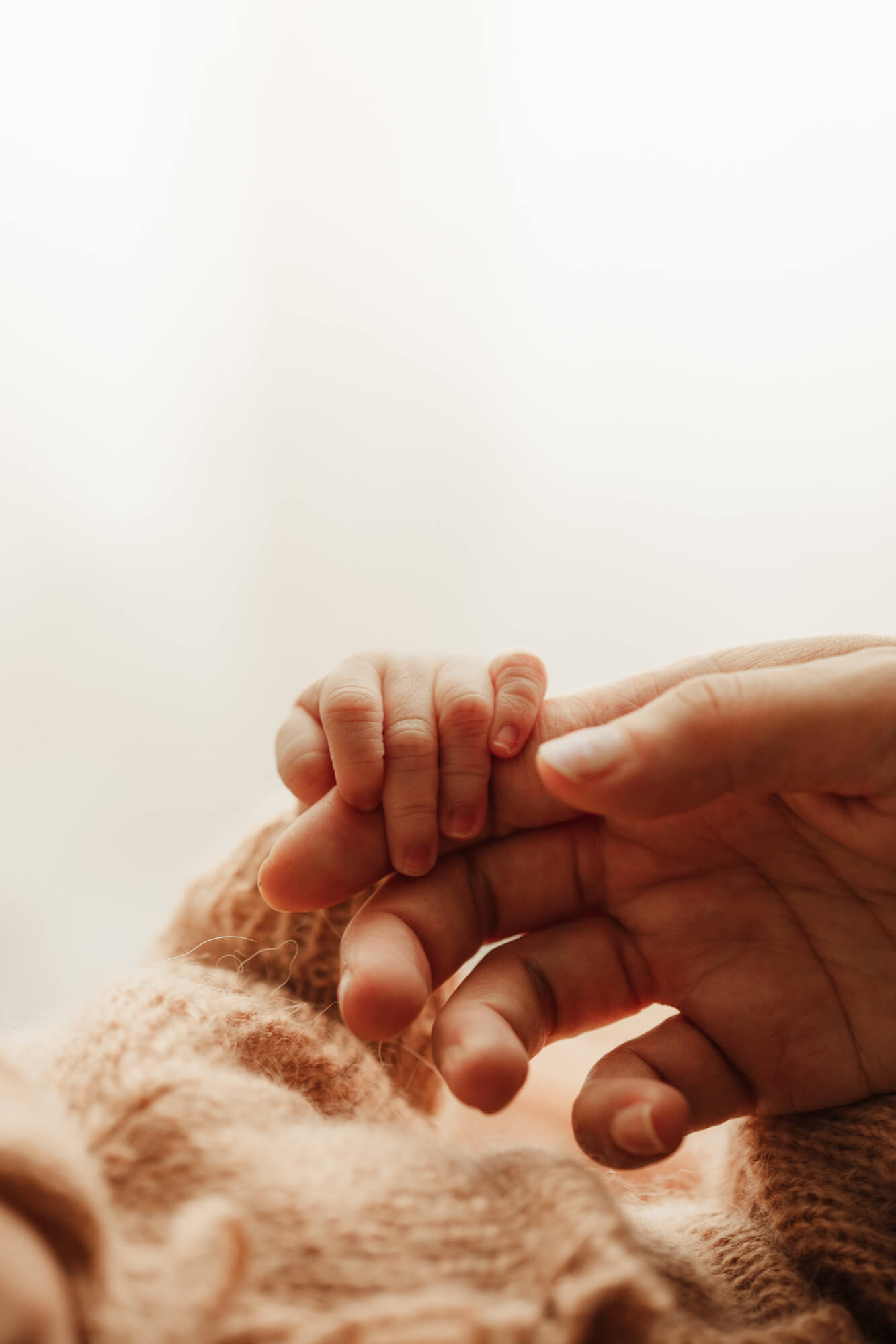 Mother's hand holding a baby's hand.