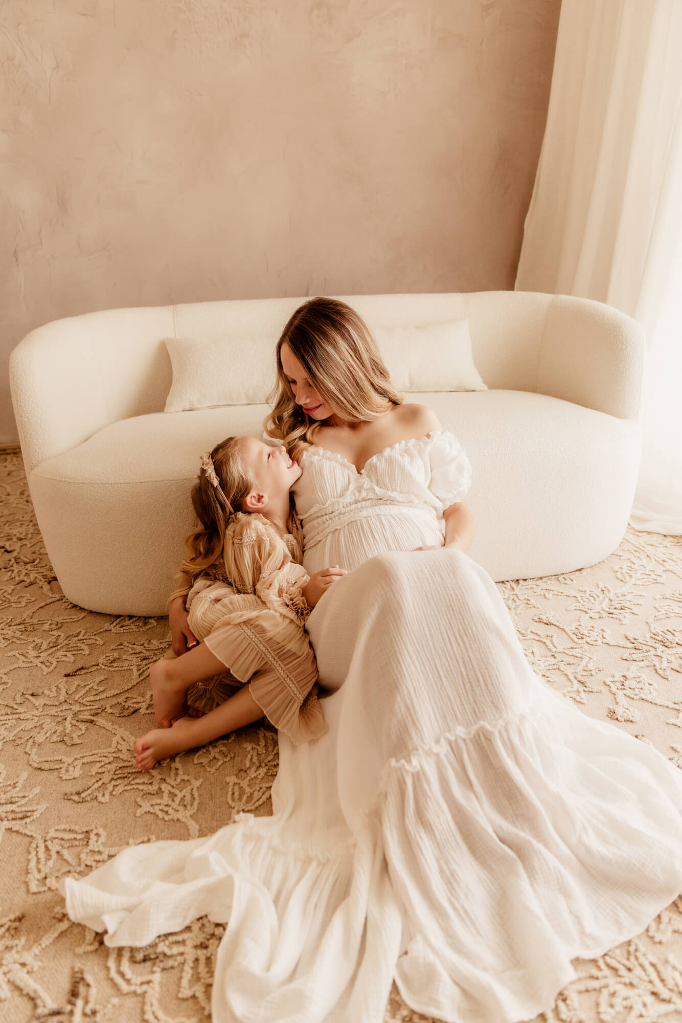 Mother and daughter smiling at one another next to a white loveseat, OBGYN Oklahoma City OK.