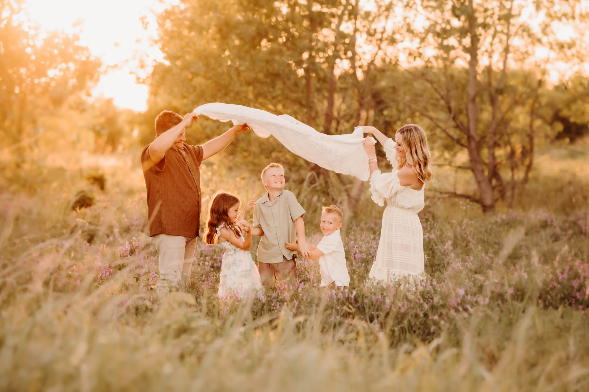 Family with three kids playing under a blanket, OKC family fun.