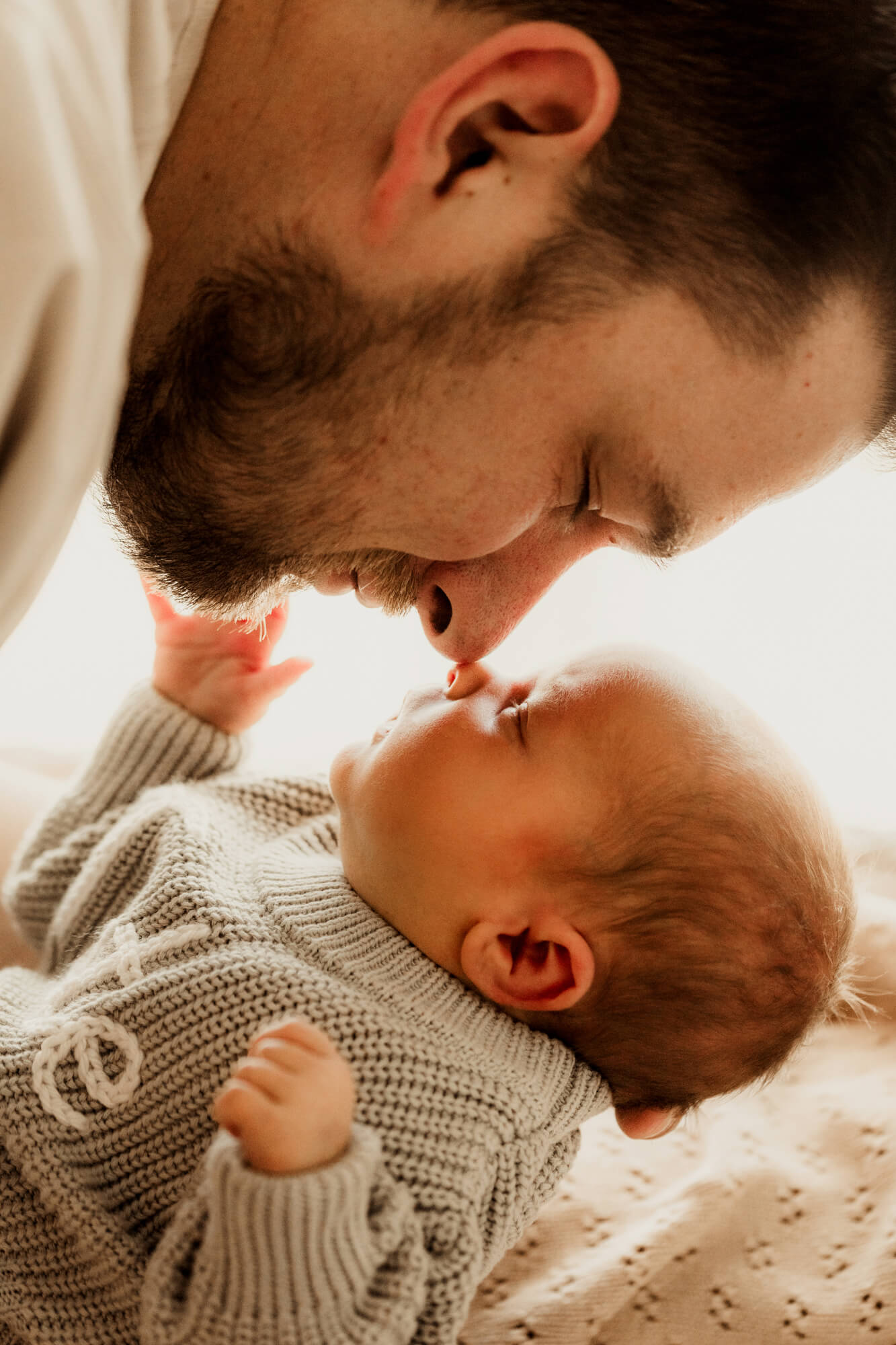 Father touches his nose to baby boy's nose.