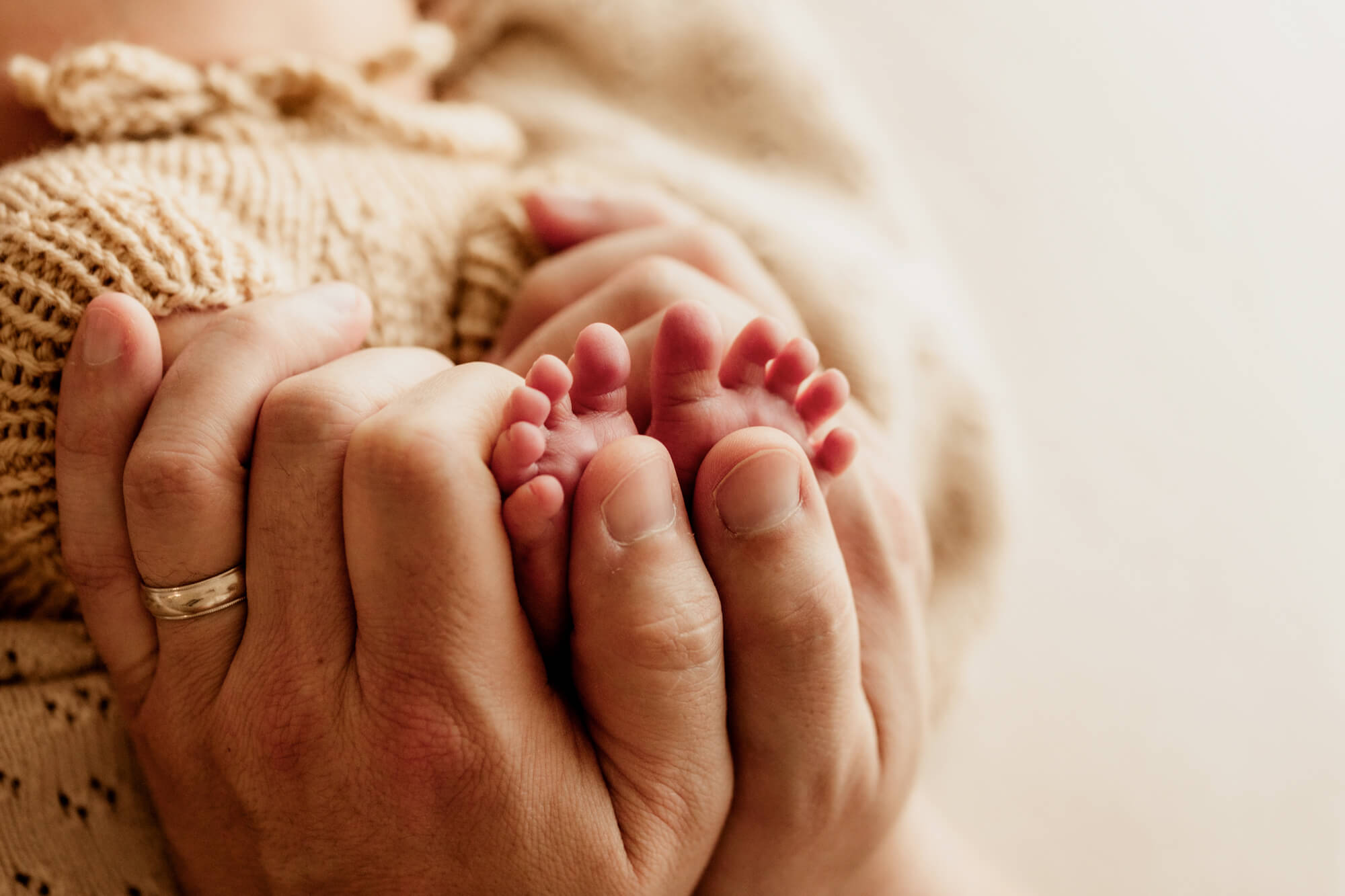 Father holding newborn baby toes with his hands, Oklahoma City 3D ultrasounds.
