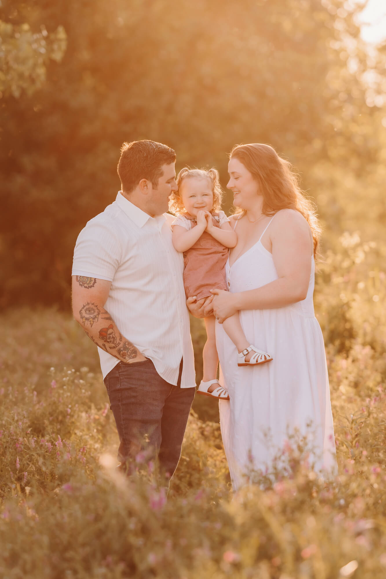 Girl with curly hair smiles with her hands by her face with her mother and father, kid friendly restaurants in OKC.