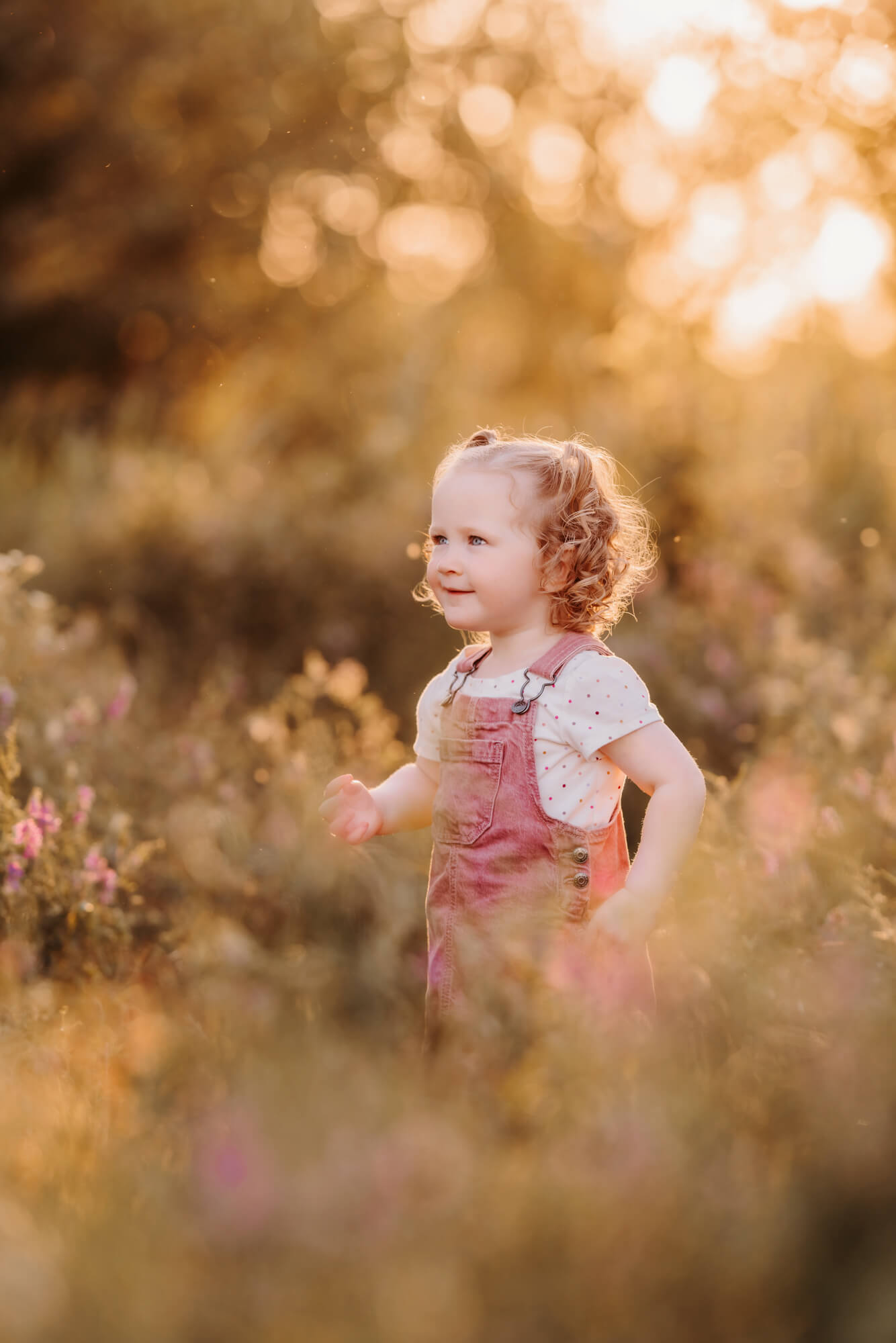 Bond hair toddler smiles off into the distance.
