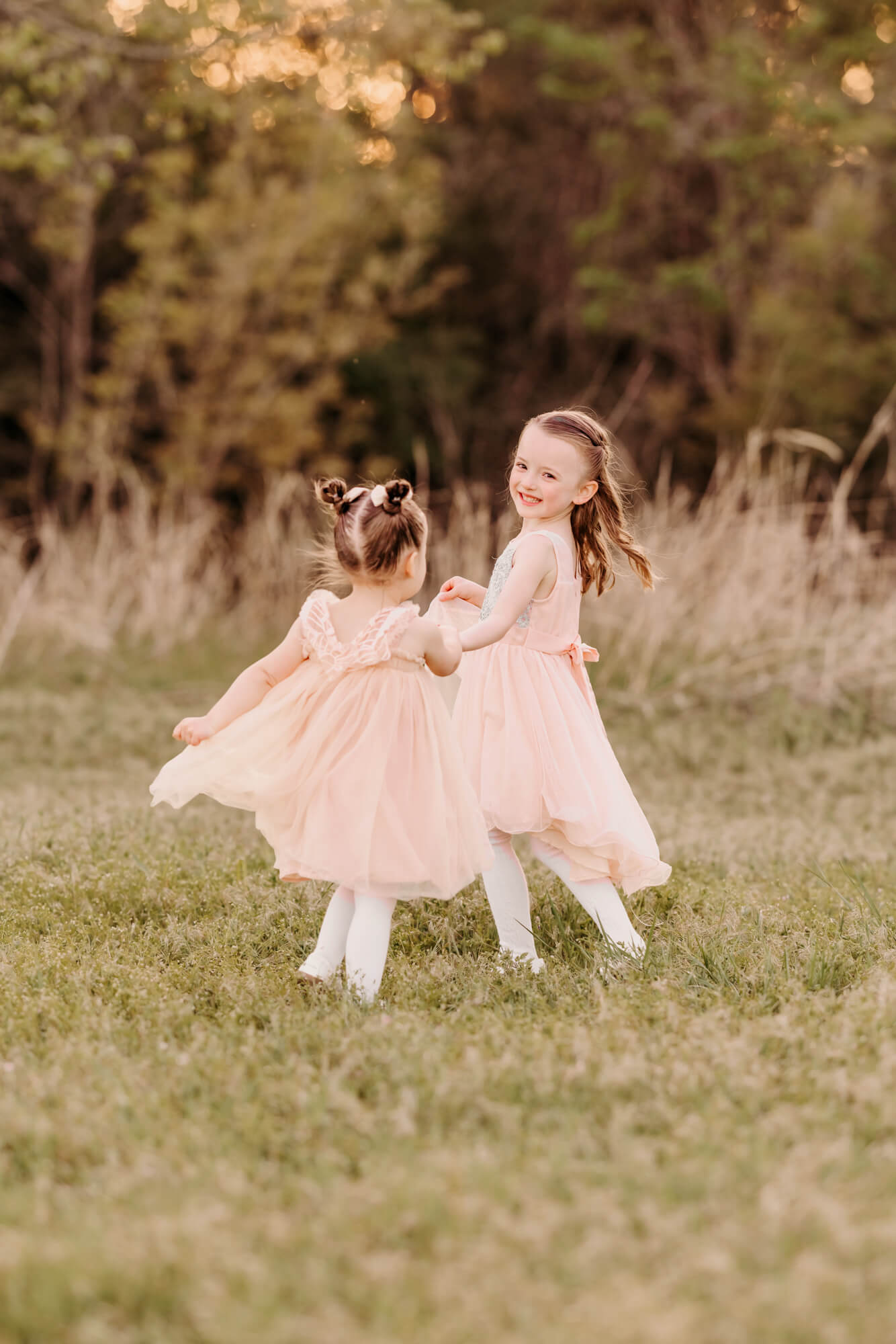 Sisters holding hands spin and play outside in Edmond, Oklahoma.