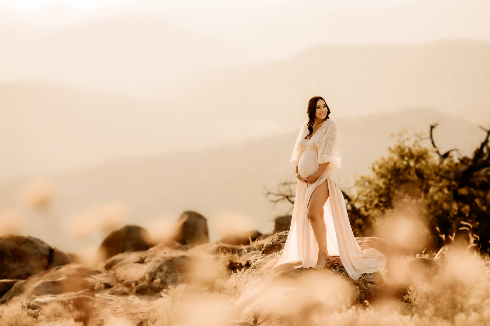 Pregnant woman wearing a white dress with mountains in the background, Perinatal Center Tulsa.