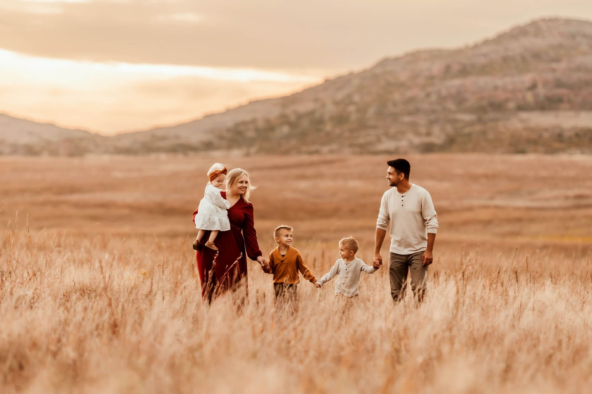 Family holding hands while walking together in a field, Kidoodles Norman OK.