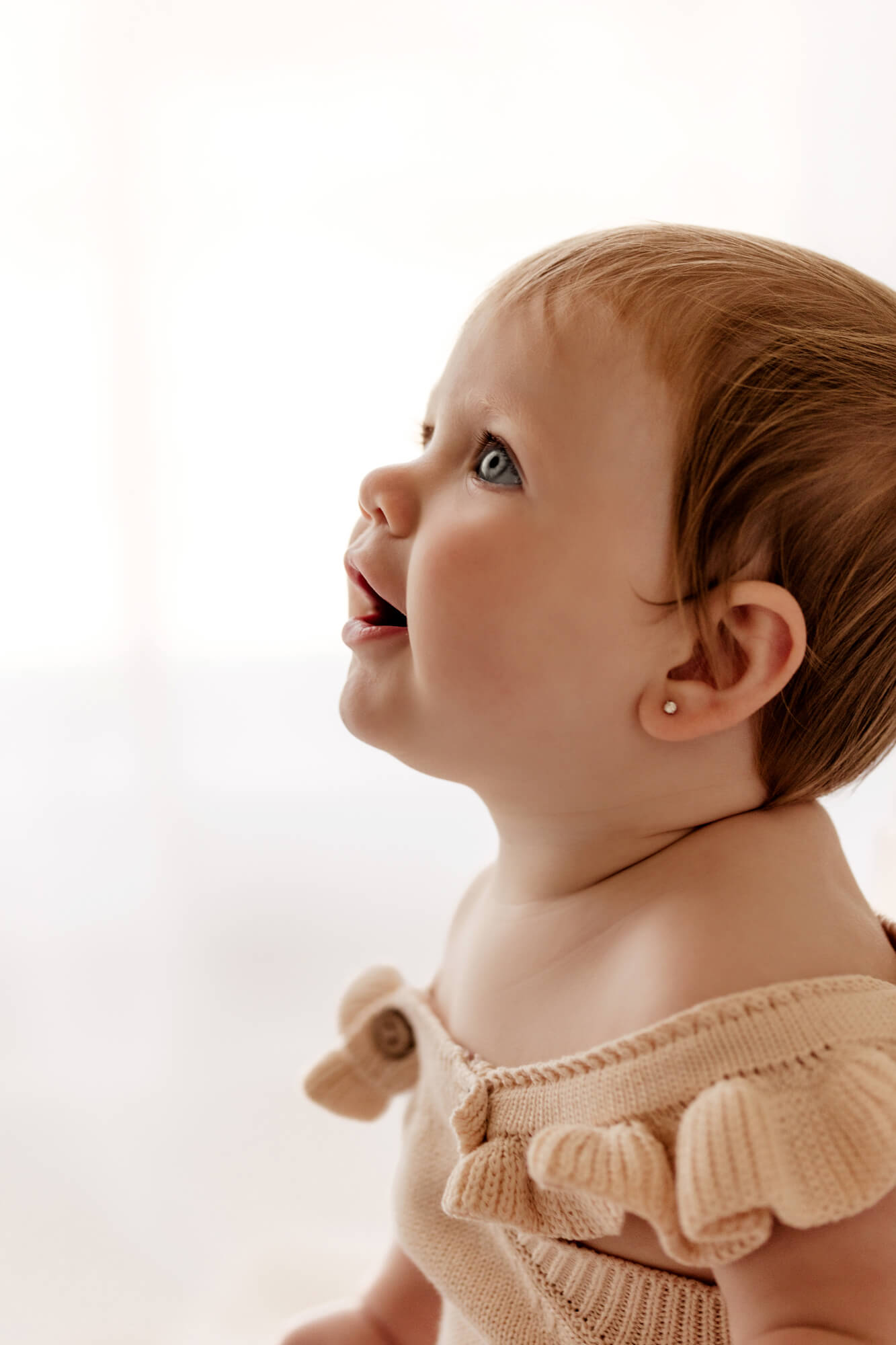 Profile image of a one year old baby girl with blue eyes looking up, OKC birthday party.