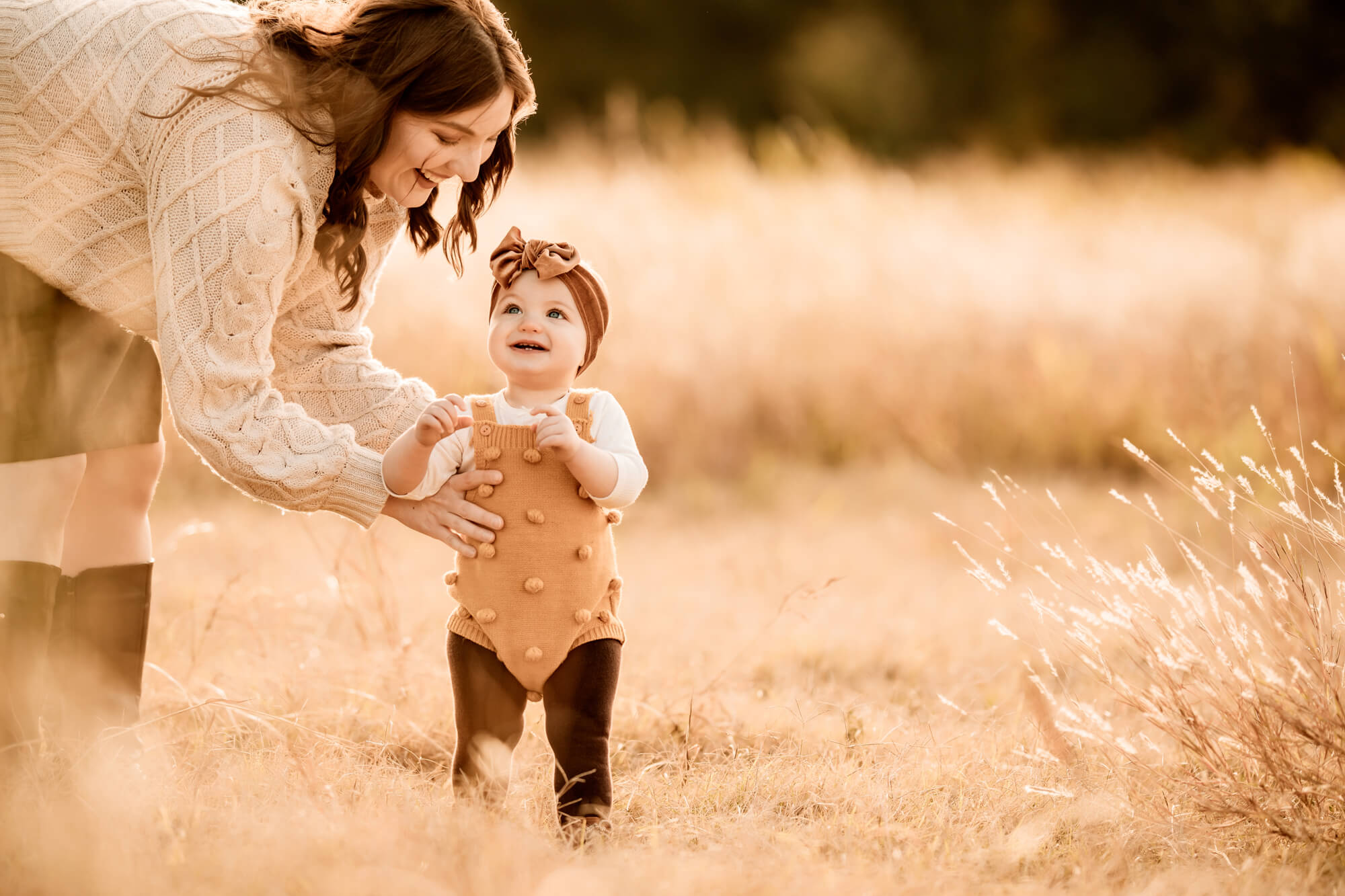 Mother smiles down at her one year old daughter standing in a field, OKC pumpkin patch