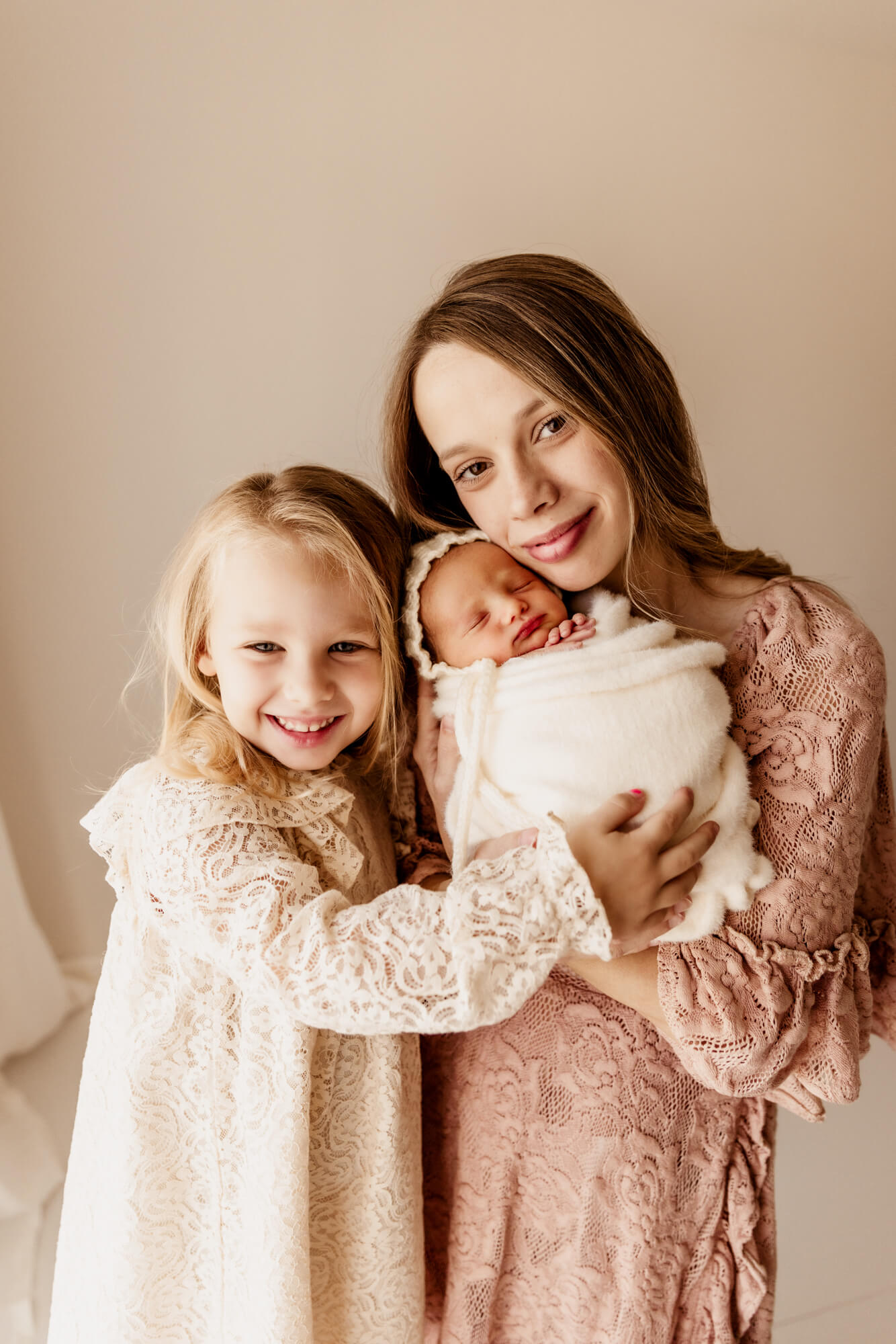 Mother smiles with her two daughters including her newborn baby girl, postpartum doula OKC.