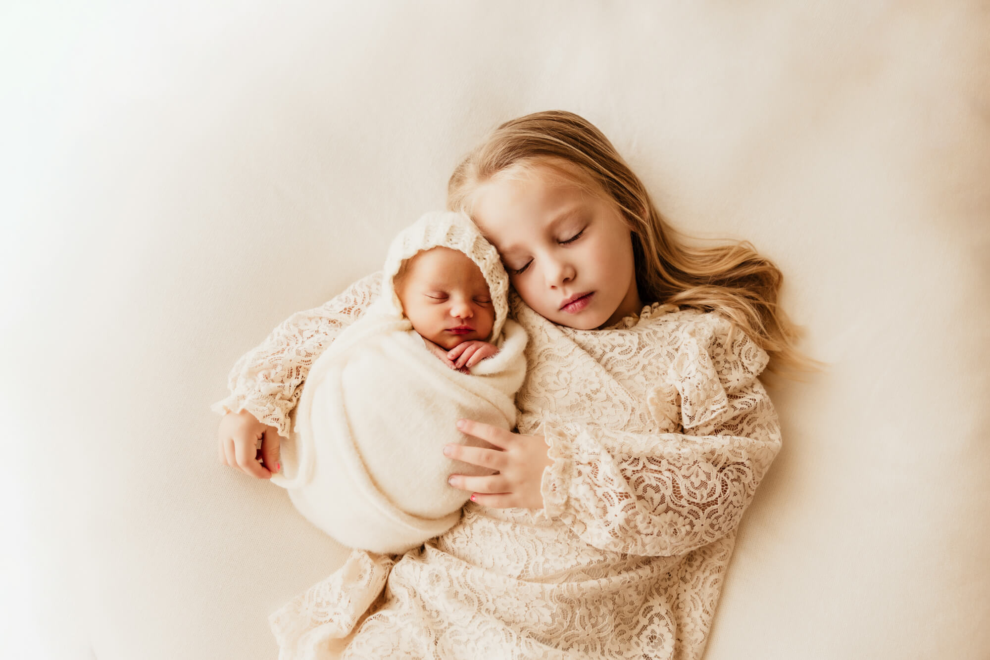 Sister closes her eyes next to her newborn baby sister.